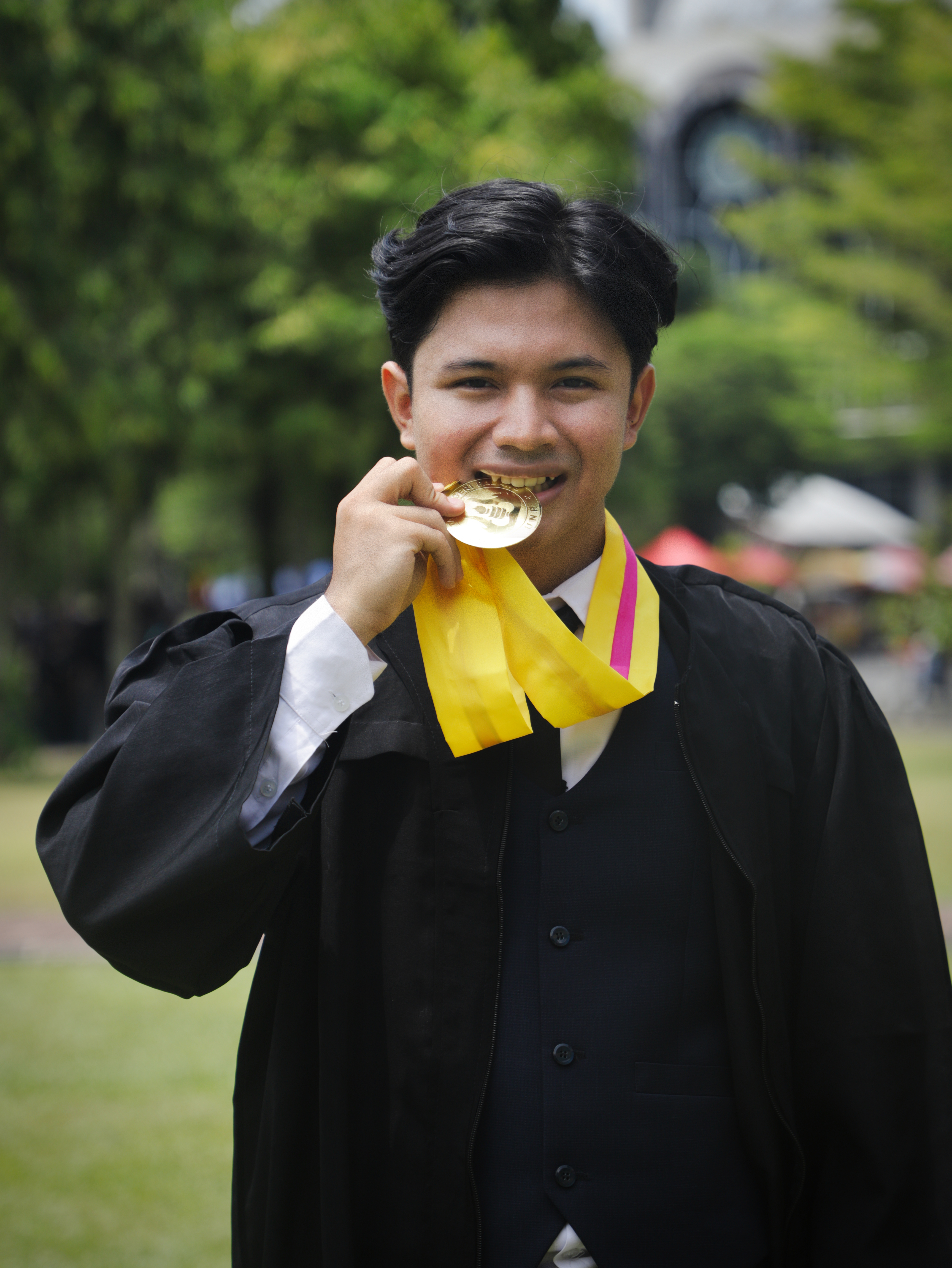 Selebrasi wisudawan menggigit medali kelulusan di kampus